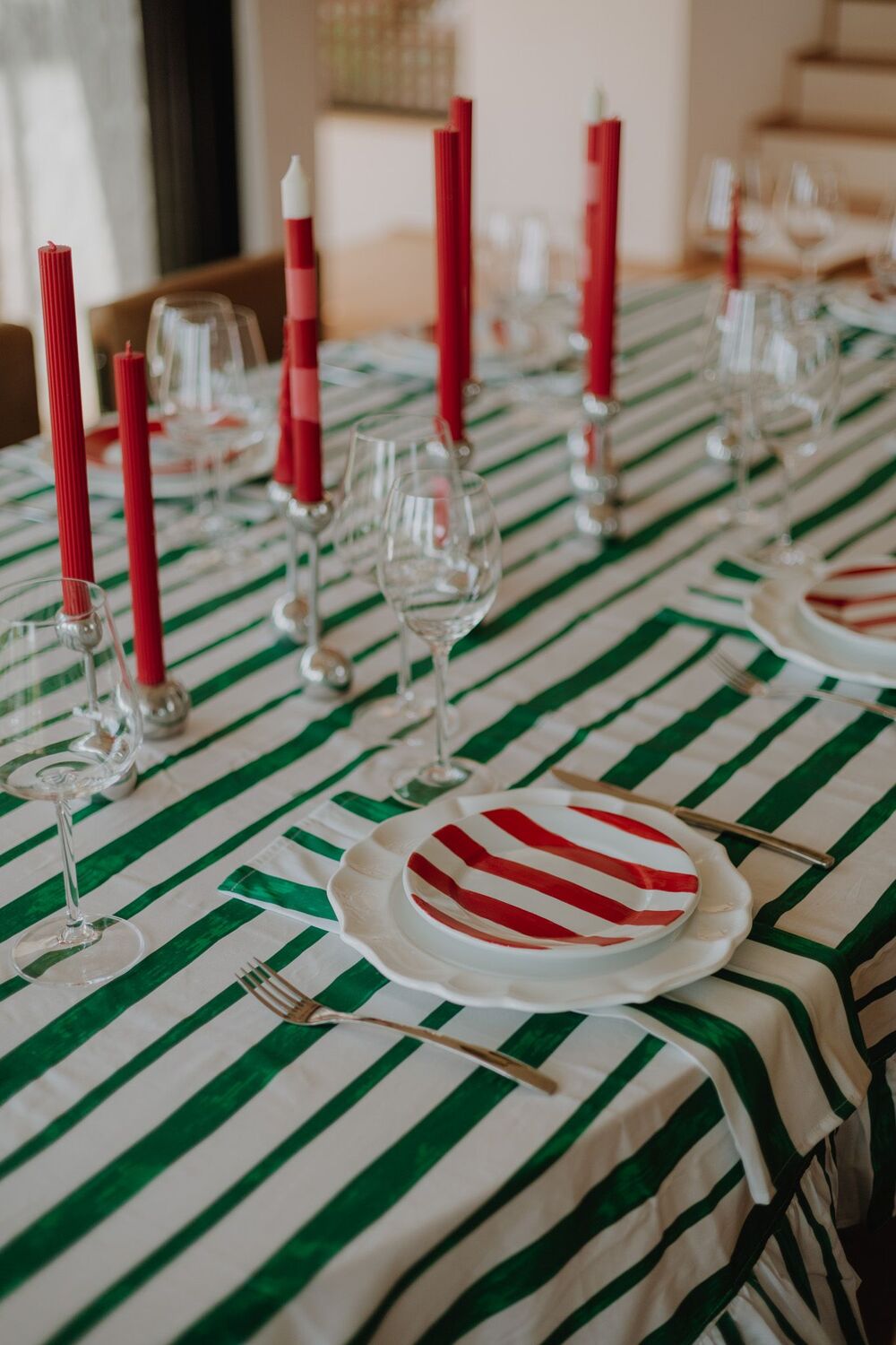 Mesa de natal decorada com velas vermelhas, taças, pratos e talheres